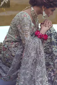 Light grayish fawn net maxi and dupatta. Bridal maxi adorned with silver, light golden, antique shades and colorful thread embellishment. Light grayish fawn net dupatta adorned with embellished border and large motifs all over it. Blackcurrant velvet sharara adorned with silver and light golden embellished border.