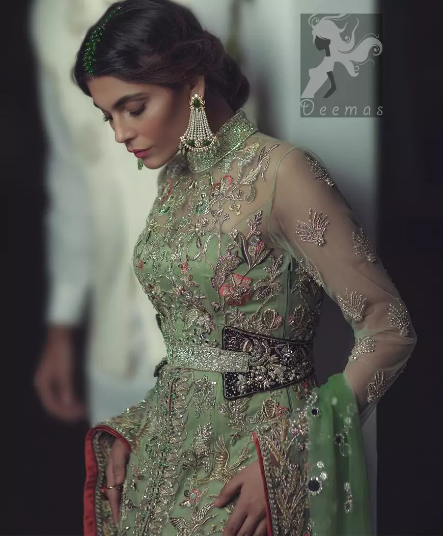Pistachio green gown having high neck gown. Embellished Bodice with waist belt and front open slits. Mehndi green trousers having embellishment on cuffs and motifs. Pistachio green net dupatta having embellished border and round motifs all over it.