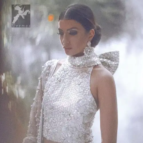 White choli/blouse having beautiful embellishments in white, silver, and maroon brown. Halterneck design has been implemented on blouse / choli.