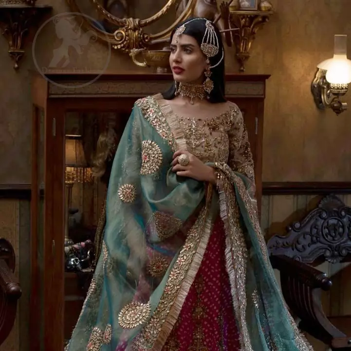 This outfit is a timeless beauty. Its blouse is heavily embellished with silver gold kora, dabka, sequins and swaronski crystals. This exquisite blouse is fully decorated with floral motifs patterns all over it. Boat shaped neckline add to the look. It comes with shocking pink chunri lehenga which has small sized sprinkled floral motifs all over. This outfit is beautifully coordinated with organza dupatta. Dupatta is embellished with kiran lace and gotta work on sides.