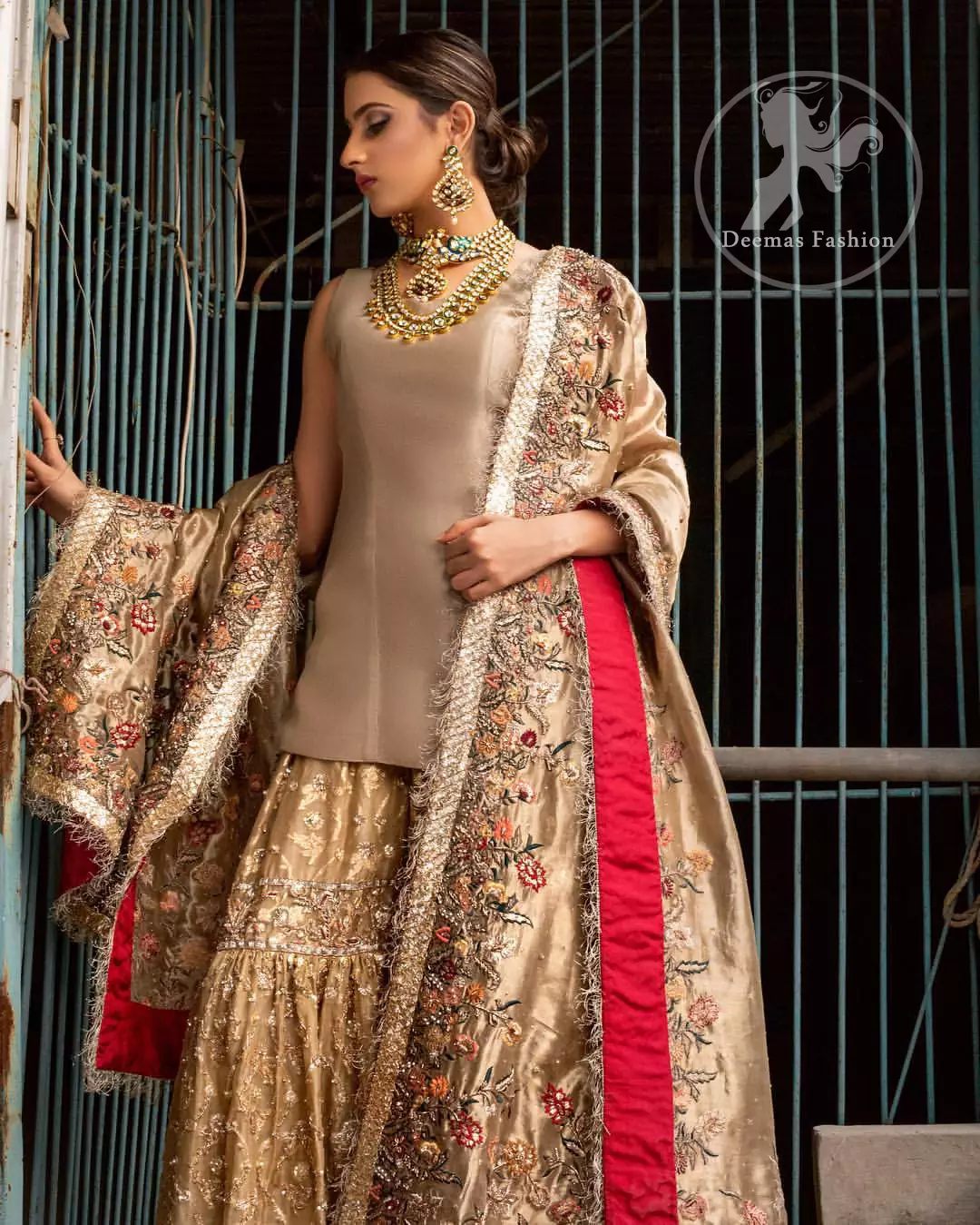 Ivory plain shirt is paired up with golden traditional gharara done with floral motifs all over. It is beautifully matched with golden dupatta with colorful embellished motifs at both lengths and lace border finished around dupatta.