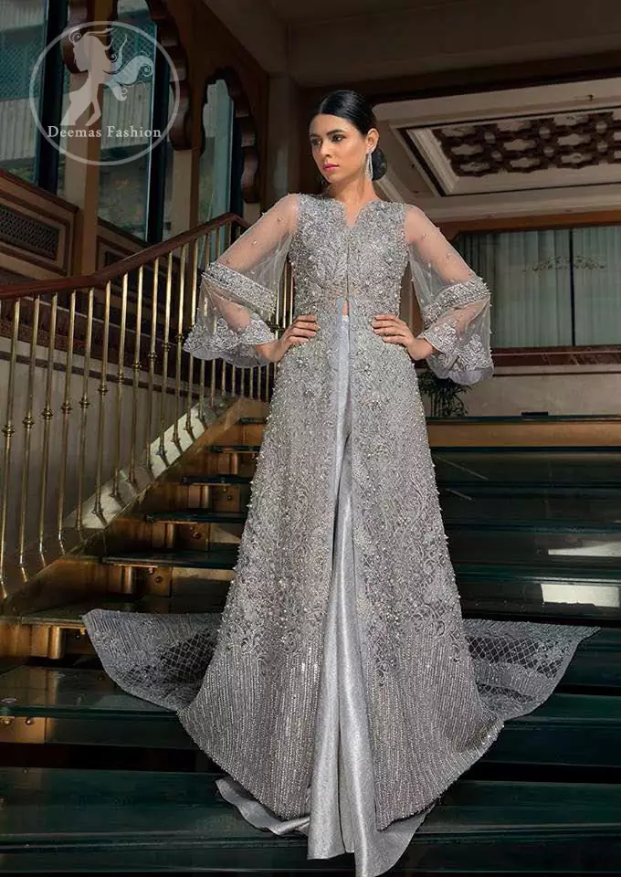 This dress is timeless beauty. Light gray, dress with heavy embellishment with swarovski crystals and silver work in sequins, kundan and kora dabka. The back trail is allured with intricate embroidered patterns and floral motifs. It is finished with light gray sharara.