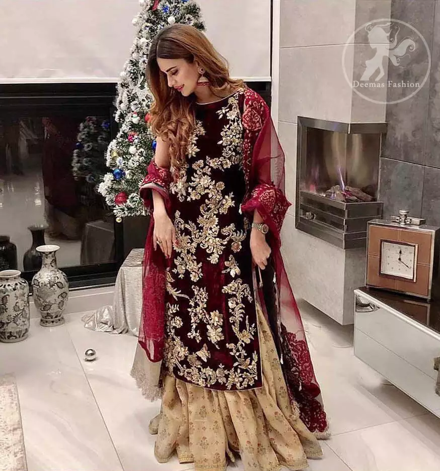 Take a step towards refreshing your wardrobe with maroon velvet dress. This maroon shirt is heavily embellished in the front with silver gold kora dabka, kundan, tilla and sequins. Finished with golden brocade self-printed gharara. This outfit is beautifully coordinates with maroon dupatta with embroidered borders on all four sides .