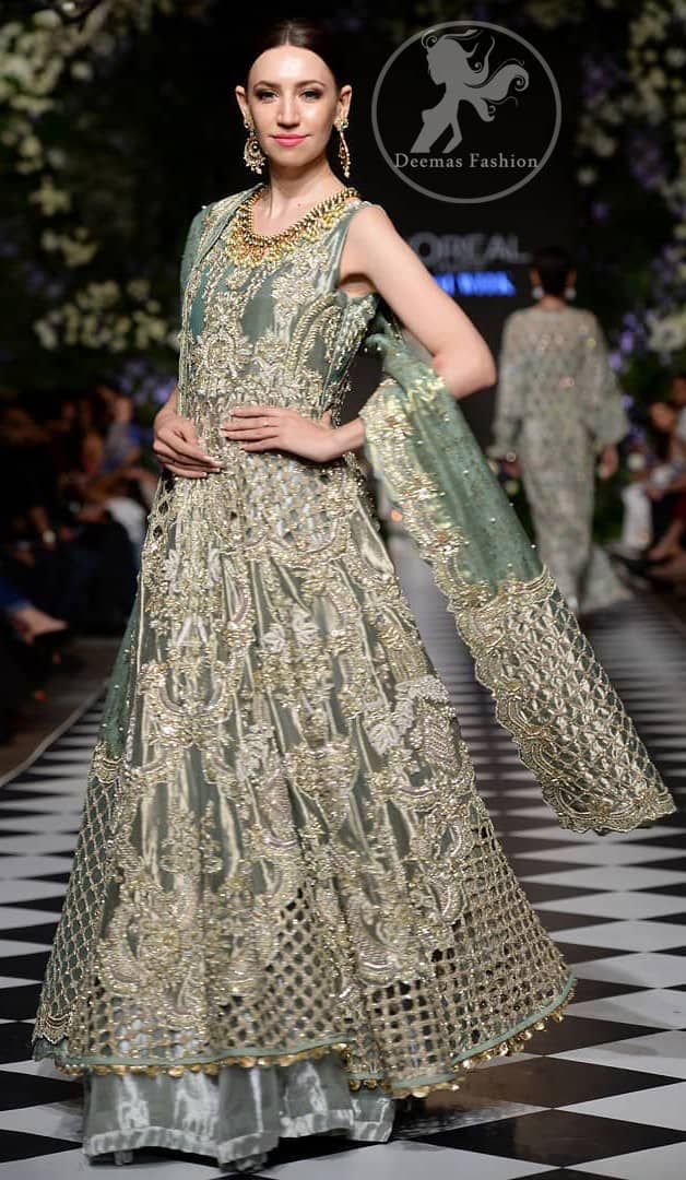 This dress is beautifully decorated with heavy embroidery. It is highlighted with dull golden kora, dabka, tilla, sequins and pearls. Fish lehengha is fully embellished.Blouse is scalloped. It comes with beautifull upper gown, sprinkled with sequins all over it. It is coordinated with chiffon dupatta which is sprinkled with sequins all over it.