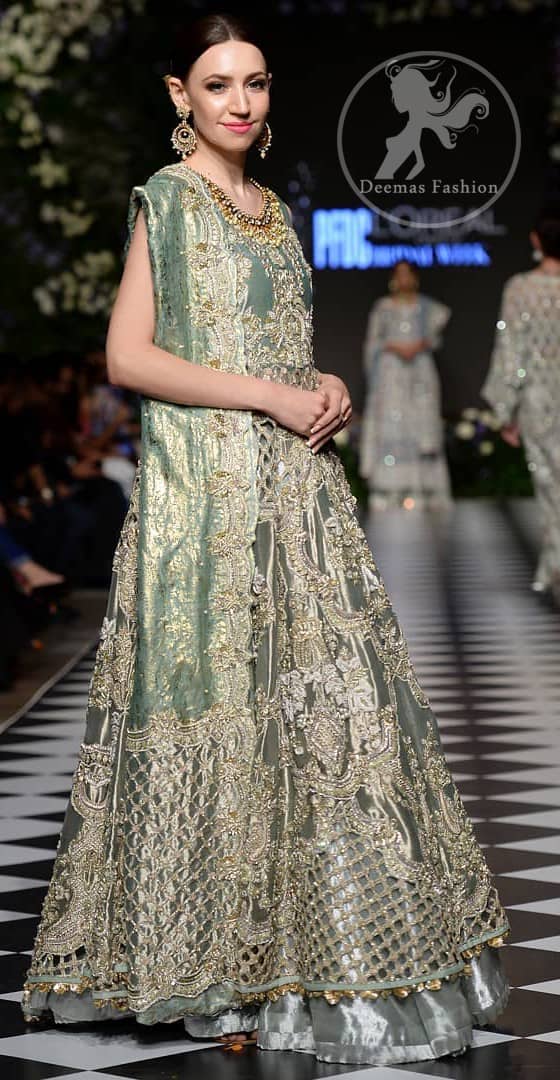 This dress is beautifully decorated with heavy embroidery. It is highlighted with dull golden kora, dabka, tilla, sequins and pearls. Fish lehengha is fully embellished.Blouse is scalloped. It comes with beautifull upper gown, sprinkled with sequins all over it. It is coordinated with chiffon dupatta which is sprinkled with sequins all over it.
