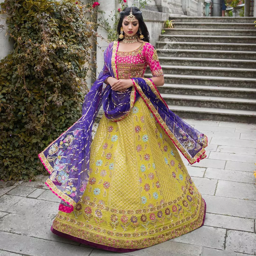 This dress is perfect for menhndi day. The shocking pink blouse is beautifully decorated with antique embroidery. It is highlighted with dull golden kora, dabka, tilla, sequins and pearls. Lehenga has small floral motifs, geometric pattern and detailed zardosi work and rich hemline. It is coordinated with purple chiffon dupatta which have verticle sequins lines all over. Furthermore it is enhanced with lace on all four sides of border.