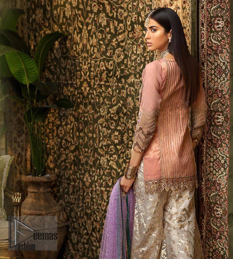 Add some super cool twist to your look with this outfit on your nikah. Gussy up in this luxuriously designed shirt emboldened with intricate embroidery along with beautiful rich patterns and delicate applique details at the daaman. Furthermore this super stunning shirt is made of rich floral embroidery which is further enhanced with zardosi work. Having full length sleeves adorned with scalloped finishing. Style it up with artfully coordinated ivory sharara finessed with lace and applique details at the bottom. The outfit is beautifully coordinated with light purple dupatta with embellished lace borders on all four sides and scattered sequins all over.