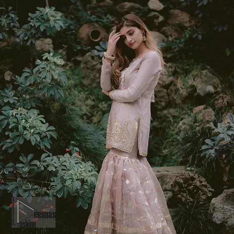 This dress is majestic beauty and perfect for your nikah or engagement day. Delicately crafted and personifying chic elegance with an element of grandiose. The beautiful neckline decorated with multiple color appliques, swarovski crystals and zardosi work. The daman is emphasized with golden kora, dabka,tilla and gota work to convey a classic look. Having full length sleeves adorned with tiny motifs scattered all over. This outfit is coordinated with self printed organza gharara. Pair it up with matching organza dupatta.