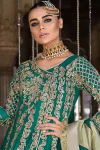 Steal the moment with our emerald green floor length angrakha emphasized with traditional neckline and intricate floral daman enhanced with light golden kora, dabka and sequins. The detailed zardosi work on sleeves and vertical panel stripes ornamented with gold kora and dabka embroidery on the bodice, the thick borders and floral bunches refined the classical royal look. Style it up with organza dupatta adorned with four sided kiran.
