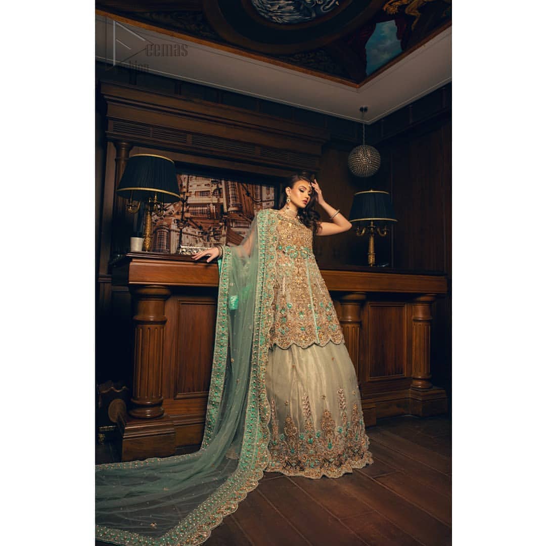 Classic, timeless and truly beautiful. Upholding the idea of simple is beautiful, you would definitely want to wear this outfit for your next occasion. The front open short frock is adorned with delicate arrangement of hand embellished floral patterns with multiple color thread embroidery and antique shaded zardozi work. The scalloped hemline done with champagne embellishment gives the right amount of glamour to the outfit. It coordinates with light fawn lehenga with scalloped bottom and heavy embellishment on it with zardozi. The look is completed with mint green organza dupatta with detailed work on the borders.