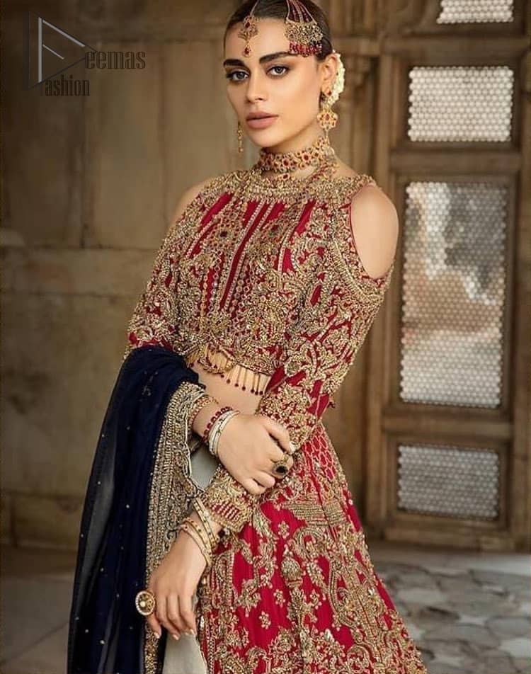 A breathtaking red traditional lehenga paired with a detailed blouse, equally alluring make for an ensemble which is comfortably chic. The blouse is done with golden and antique shaded embroidery and finishing with tassels. Blouse having cold shoulder full sleeves. The lehenga is enhancing with the art of classical heritage showcasing the craftsmanship of kora, dabka, tilla, kundan and sequins detailed, artistically embellished to give a beautiful rhythm to the outfit. It comprises with navy blue dupatta sprinkled with sequins and four sided scalloped border. This is an ensemble that is sure to invite compliments galore.