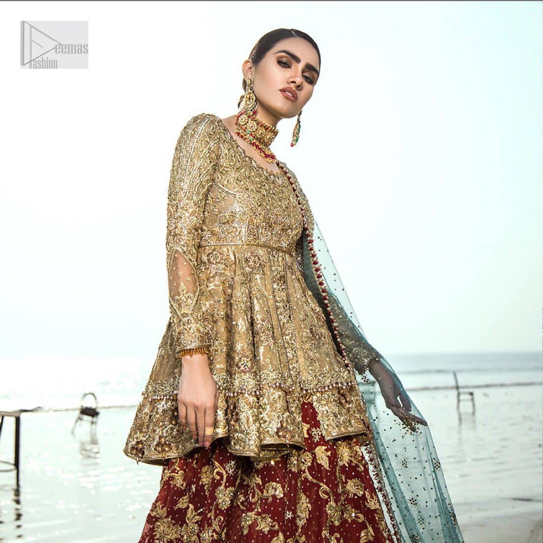 This wedding season, create a blissful aura with the treasure of love and elegance. An artistic vision of classic style and luxurious detailing infused with a bohemian spirit, transpire into a truly romantic and iconic bridal for your big day. The golden double layered peplum is heavily laden with zardozi and the perfect blend of traditional flamboyance and modern elegance in design. Pair it up with maroon lehenga enhanced with golden zardozi work. To complete the look, go with teel dupatta scattered with sequins all over the ground and heavily embellished borders to give it a perfect maharani look.