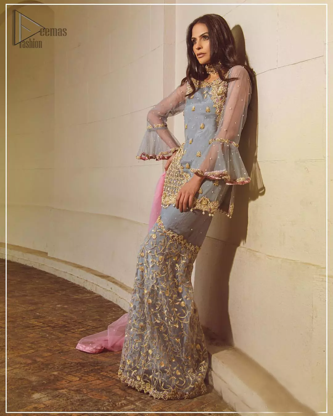 Embrace the season of festivities with this beautiful dress. The chic yet elegant outfit is decorated with golden embroidery, embellished neckline and tiny floral motifs. Borders are even more enhanced with golden zardozi detailed patterns and finished with scallops and dangling balls. Pair it up with gray sharara highlighted with floral jaal and scalloped bottom done with golden kora, dabka and tilla work. The look is complete with pink net dupatta sprinkled with sequins all over.
