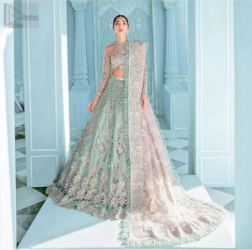 A enchanting amalgamation. This fairytale ensemble is everything that you need to impress everyone. The fusion of rich fabrics intricately designed with floral powdery hue. Precious uncut stones are threaded together with silver zardozi on pastel color palette to give it an enchantingly exquisite look. The illusion neckline blouse is laden with silver kora, dabka details and pair it up with a beautiful lehenga. The lehenga is adorned with colorful chatta patti waist belt and a captivating geometric jaal finished with scattered floral motifs and scalloped hemline. Finish the look with pink dupatta focusing on heavily embellished borders on all four sides to give it a perfect maharani look.