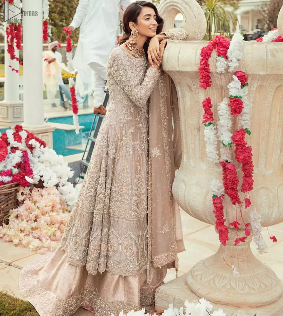Bringing traditional charm to your big day with intricately silver and light golden embellished neckline and thick worked lines all around the flare on Tea rose canvas of Pishwas. Tea Rose pure Organza Pishwas adorned with heavy embroidery all over it. The nikah Pishwas has beautiful danglings on the back of the neckline and it comes with a pure banarsi jamawar lehenga having large thick borders on the hemline. This nikah wear tea rose Pishwas, pure banarsi jamawar lehenga comes with pure organza embroidered border dupatta.