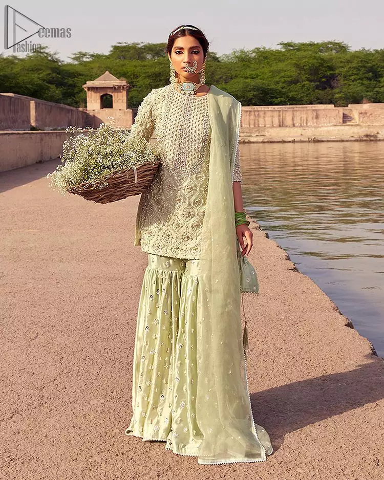Glow up an evening formal event with a Light Parrot Green Gharara Shirt, a beautiful three-quartered sleeves shirt designed with the most accurate round neckline to make you appear the star of the night. But a star as beautiful as you need to sparkle bright, which is why the dress is adorned with an outstanding work of silver and gold embroidery and ornamented with glittering pearls. This beautiful dress is designed in a matching embellishment with criss-cross patterns to help you dress up precisely. Finally, an organza dupatta concludes your magical gorgeousness.