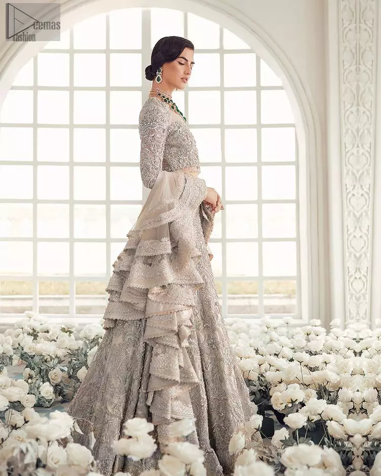 Your wedding day becomes more memorable when the guests are stunned by your majestic beauty and the perfect arrangements that are made. The Cream Lehenga Blouse is designed with such dexterity as to make you one gorgeous-looking bride on your big day. The dress code demands a full-sleeved blouse with a unique sweetheart neckline. Its exquisite fawn colour is meritoriously adorned with superb silver embroidery and stylish tassels, which are indeed the most graceful works of matching embellishment. When it comes to the definition of elegance, the purest organza is specifically reserved for the creation of such marvellous attire. Followed by a beautiful dupatta and a lehenga, this charming bridal wear will make your Walima or Nikkah a heavenly day.