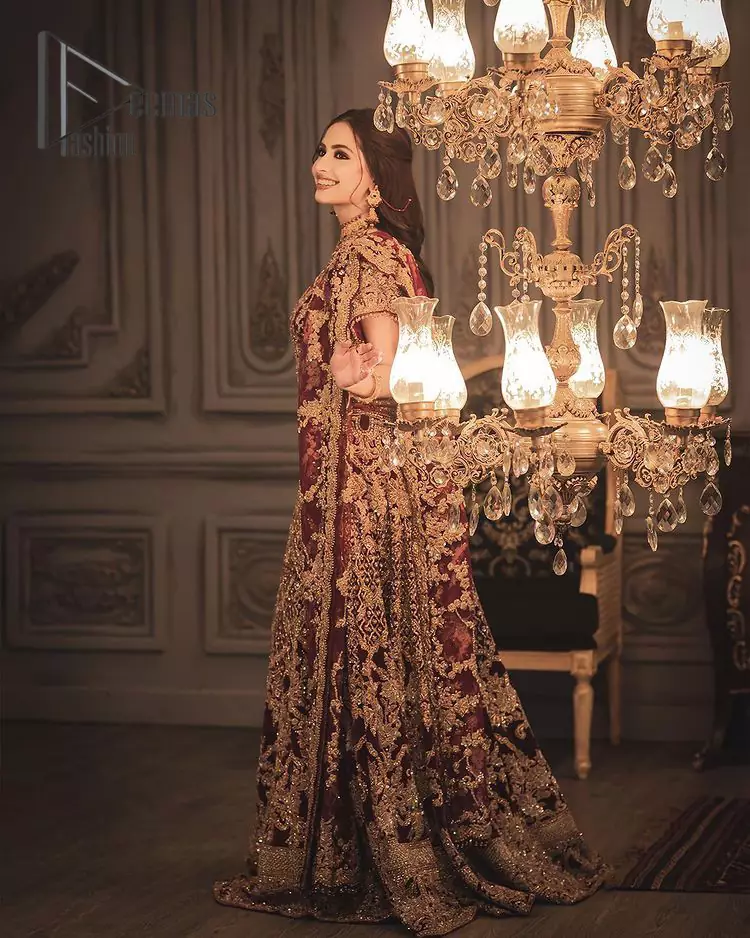 With the right outfit, every bride can rule the world! As nothing makes a bride more beautiful than the trust of her outfit. Introducing maroon half sleeves blouse that is fully embellished with tilla, kora and dabka work. In addition to this, the boat shape neckline of this blouse that is made with pure velvet gives you a dreamy look. It is synchronized with a velvet lehenga that is adorned with priceless heavy embroidery. Finish this look with an organza dupatta, embellished with embroidered scalloped borders to give you a relaxing and soothing look at your reception.