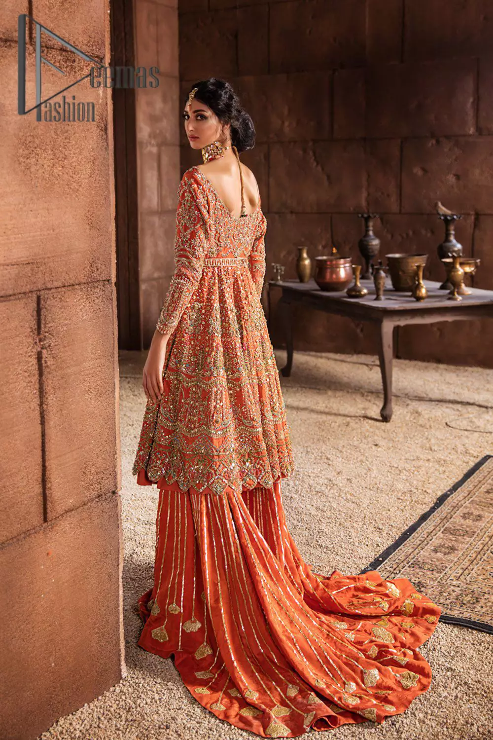 Fall in love with elements of detailing. Embrace your Mehandi style story with this orange attire serving vogue at its best. This orange frock is attractively adorned with golden embroidery that is further highlighted with kora, dabka, tilla, and antique work. And the scalloped border of the frock is just amazing so you can steal everyone's heart. In addition to this when the boat shape neckline combines with full sleeves it gives a super aesthetic scene. It is beautifully paired up with back train sharara that makes you a focus star of the day.