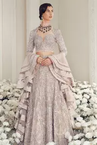 Your wedding day becomes more memorable when the guests are stunned by your majestic beauty and the perfect arrangements that are made. The Cream Lehenga Blouse is designed with such dexterity as to make you one gorgeous-looking bride on your big day. The dress code demands a full-sleeved blouse with a unique sweetheart neckline. Its exquisite fawn color is meritoriously adorned with superb silver embroidery and stylish tassels, which are indeed the most graceful works of matching embellishment. When it comes to the definition of elegance, the purest organza is specifically reserved for the creation of such marvelous attire. Followed by a beautiful dupatta and a lehenga, this charming bridal wear will make your Walima or Nikkah a heavenly day.