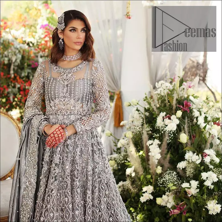 Walking into a new chapter of your life with the joy of togetherness and the magic of love. DeemasFashion presents a silver-grey maxi for your walima day that is handsomely adorned with a silver embroidery that comprises tilla, kora, dabka and crystal work. It is featured with a round neckline and full sleeves that grant you the feeling of joy. Parten this with back train shimmery lehenga which is beautifully organised with the same colour frill that enhances the overall charms of the unique article. Carry this article on your walima day and surprise your loved ones with this fairy look. 