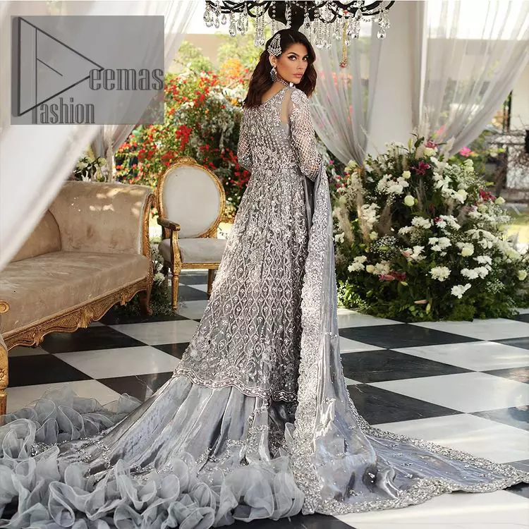 Walking into a new chapter of your life with the joy of togetherness and the magic of love. DeemasFashion presents a silver-grey maxi for your walima day that is handsomely adorned with a silver embroidery that comprises tilla, kora, dabka and crystal work. It is featured with a round neckline and full sleeves that grant you the feeling of joy. Parten this with back train shimmery lehenga which is beautifully organised with the same colour frill that enhances the overall charms of the unique article. Carry this article on your walima day and surprise your loved ones with this fairy look. 