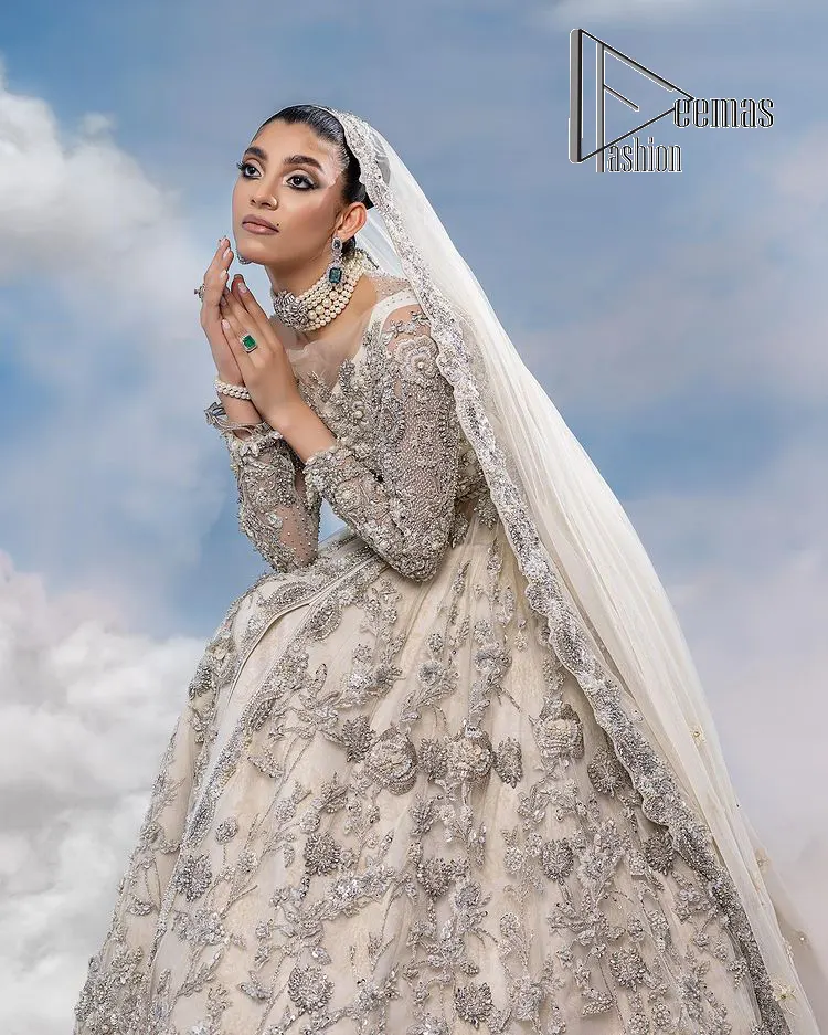 The mind wears the colours of the soul, as a beige of those of his master. Starting this nikah outfit with a beige frilled maxi which is laboriously hand-rendered with silver embroidery to fulfil the fairy dream of every bride. Furthermore, it is enhanced with tilla, dabka, kora and crystal which magnifies the beauty of this nikah outfit. The illusion neckline looks as amazing when comes with full sleeves as the moon with stars. The maxi of this nikah outfit is systemized with a lehenga in the same colour which is proof of uniqueness. Complete this nikah outfit with a dupatta in the same colour having a four-sided embellished border and sequins sprayed all over.    