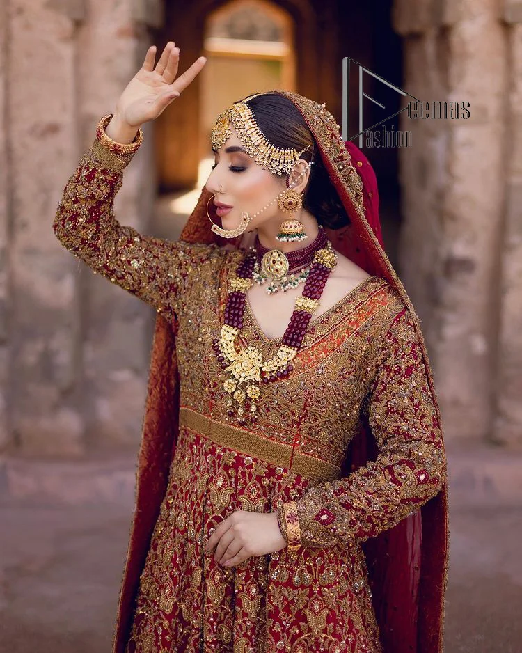 Happy is the bride the maroon shines on. Initiate this Pakistani reception outfit with a maroon heavy Anarkali which is sumptuously hand-rendered with golden embroidery that includes tilla, dabka, kora and Kundan. The V shape neckline of this Pakistani reception outfit exquisitely comes with full sleeves. It is paired up with rust farshi lehenga whose border is again adorned with golden embroidery. Finish this Pakistani reception outfit with a dupatta with a four-sided embellished border and sequins sprayed all over to put a maroonish shine on your big day.