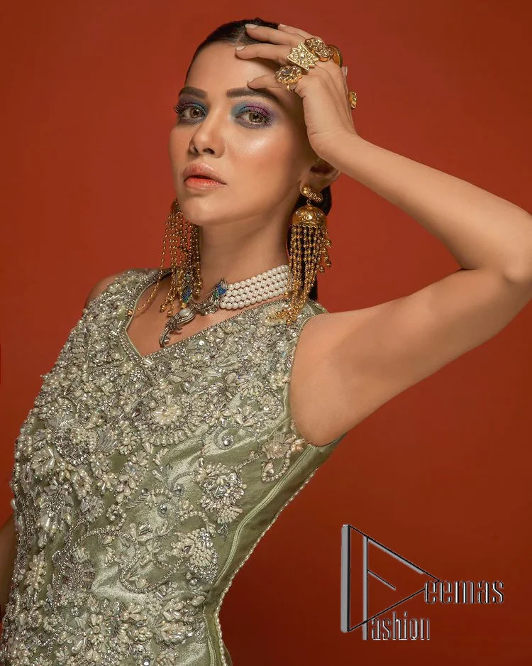 Celebrate your party events with DeemasFashion. An olive green shirt in tissue fabric, hand embellished with dabka, nakshi, cut dana, Resham, Swarovski, Mukesh, sequin and Kundan. A heavily embellished bodice featuring floral patterns all over to make your party event marvellous and shiny. The following heavy shirt is enhanced with V shape neckline along the sleeveless style. The bottom of the shirt has handsome fringes to give you a charming and splendid look.