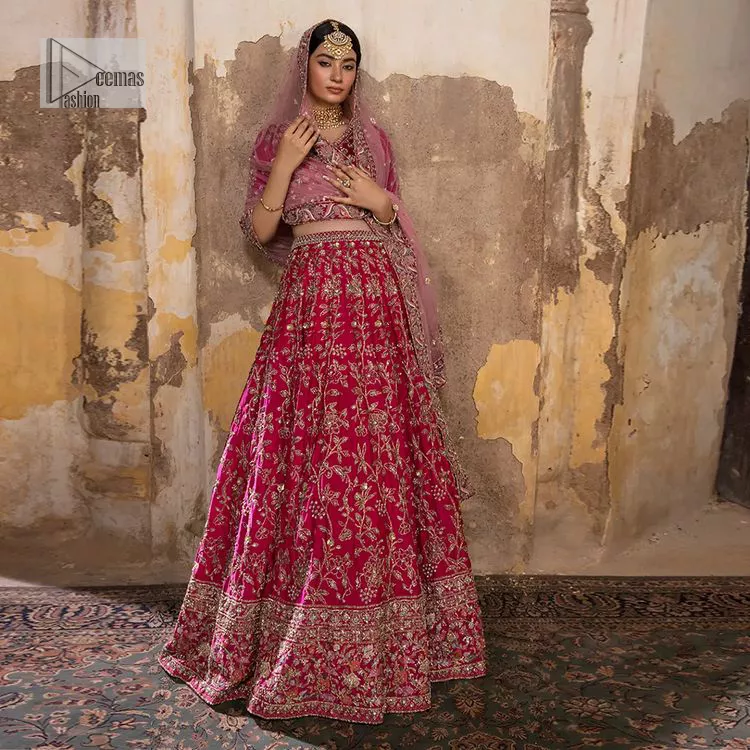 Blissful Pink! This ensemble is the epitome of grace. A shocking pink lehenga is heavily adorned with floral patterns. The flare of the lehenga gives a ravishing finishing look to this party wear. A beautiful blouse in the graceful shocking pink shade is an exquisite choice to pair with Lehenga. This choli is hand-embellished with lavish details of golden embroidery which is highlighted with dabka, tilla, kora, Kundan and details of Resham. Floral designs on half sleeves give a beautiful traditional touch to the masterpiece. It is paired up with a dupatta embellished with four-sided borders and tiny floral motifs all over.