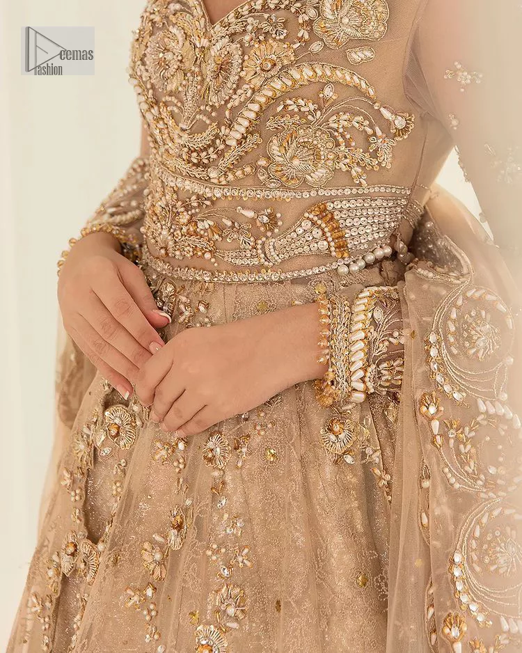 Presenting elegance personified glamorous formal nikah outfit. A heavenly-designed light golden maxi on an organza base serves as a canvas for spellbinding embellishments of antique gold, tilla, dabka, kora, Kundan and sequins. The sweetheart neckline makes this outfit unique and priceless. Furthermore, the following flawed maxi has three-quarter sleeves. It is paired with a plain lehenga and a dupatta in the same colour. The dupatta is adorned with carefully placed sequin spray and embellished four-sided borders for more calm and charm.