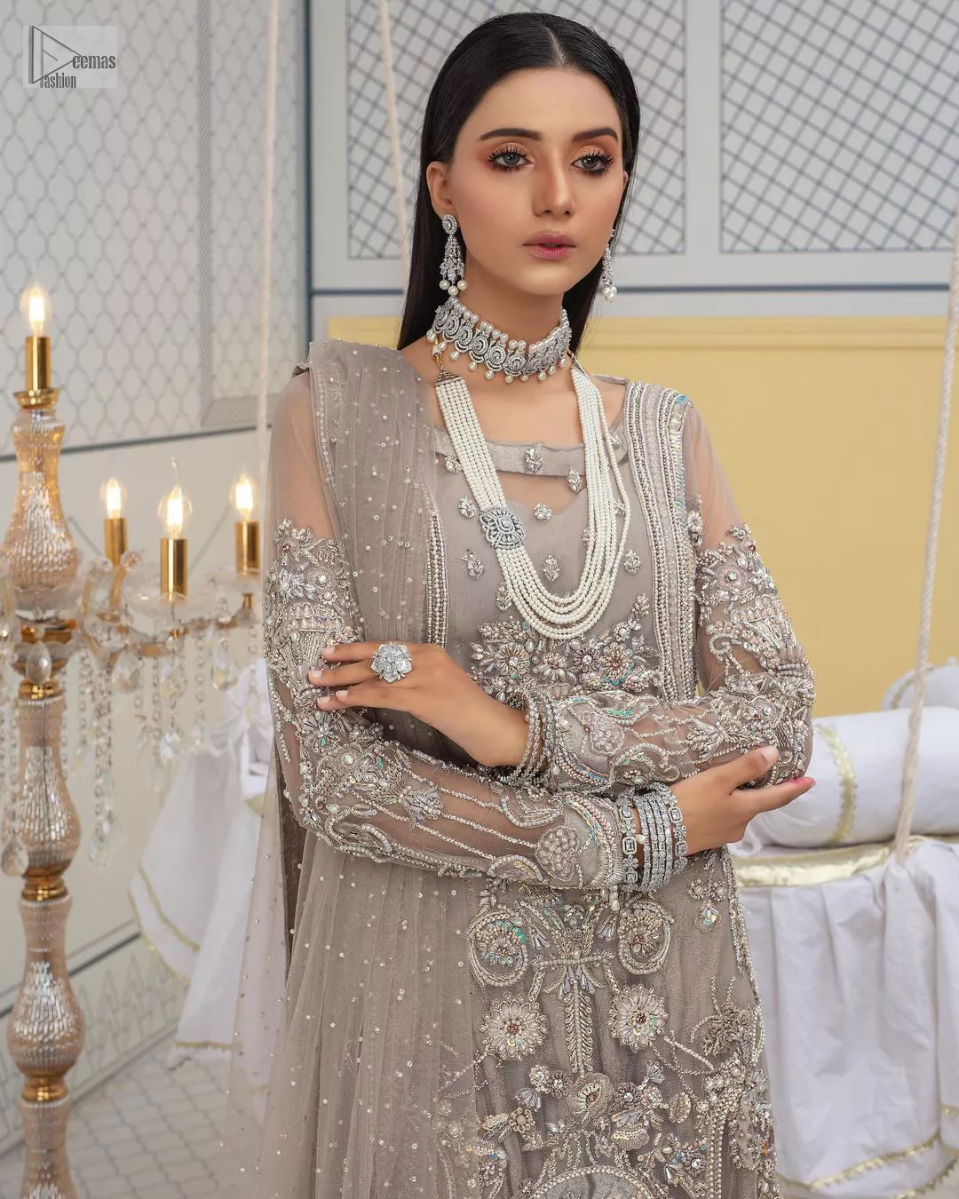 Chill vibes in grey are very rare. A beautiful grey shirt with a medley of hand-embellished floral motifs and floral patterns of silver embroidery which is highlighted with tilla, dabka, kora, Kundan and the real magic of Zardozi. The illusion neckline makes this party outfit a little romantic. Further, the floral patterns on full sleeves also add super beauty. It is paired up with plain jamawar trousers just to balance the look   Complete this gorgeous outfit with a dupatta in the same colour framed with four-sided borders and sequins sprayed all over. 