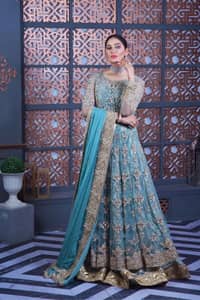 Bright colours are always a yes for a walima outfit. The embellished light blue maxi lehenga is an epitome of elegance and royalty that wins everyone's hearts at the very first glance with its charm and elegance. Hand-crafted details of golden and silver work on the maxi which is prominent with tilla, dabka, Kora, Kundan and the real magic of Zardozi give a glamorous touch to this masterpiece. The round neckline of the following maxi is the epitome of elegance. Further, the full sleeves are also decored with floral motifs. It is paired with a lehenga to balance the outfit details. Complete this outfit with a dupatta framed with four-sided borders and sequins sprayed all over.