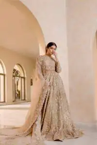 It features a softgalm-inspired look that redefines elegance.  An elegant rhyme to tradition, the attractive and beautiful walima wear lehnga choli creates aesthetical magic with its eye-catching ivory colour. The blouse shines with embellishments and an amalgamation of floral patterns in silver and golden colours. It is further intensified with tilla, dabka, kora, Kundan and the real magic of Zardozi. The boat shape neckline makes this charming. In addition to this, the floral patterns on full sleeves make this masterpiece more lovely. The perfect outfit is paired with a flared lehenga which is heavily ornamented with handsome embroidery. Complete this with an organza dupatta which is adorned with a four-sided embellished border and sprayed with tiny floral motifs and sequins all over to make your day fresh and bright.