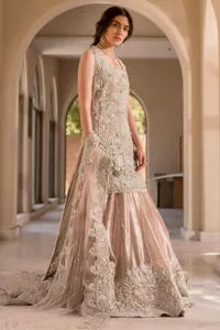The beauty of idealism is captured with a touch of sparkle. This exclusive rose pink ensemble is beautifully translated on rose pink canvas, which makes this walima outfit stand out in the crowd. This fully embellished article comes with a short shirt lehenga style that gives it a bold look. The round neckline makes this masterpiece a unique cut. The short shirt is adorned with a silver embroidery which involves tilla, dabka, kora, Kundan and the real magic of Zardozi. Further, the sleeveless style of the following short shirt adds charm to the lehenga with heavy border embellishments on it. Carrying out its final contemporary look with a net scalloped dupatta framed with four-sided embellished borders and cross lines all over.